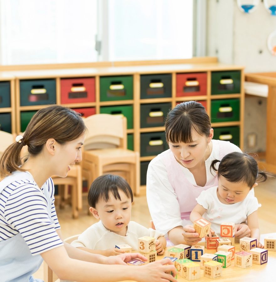 保育室で先生と木のおもちゃを使って遊ぶ子どもたち