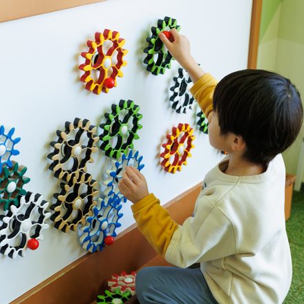 壁の知育おもちゃに夢中で取り組む園児