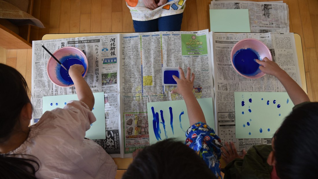 机を囲んで絵の具の制作に取り組む幼稚園部の園児たち