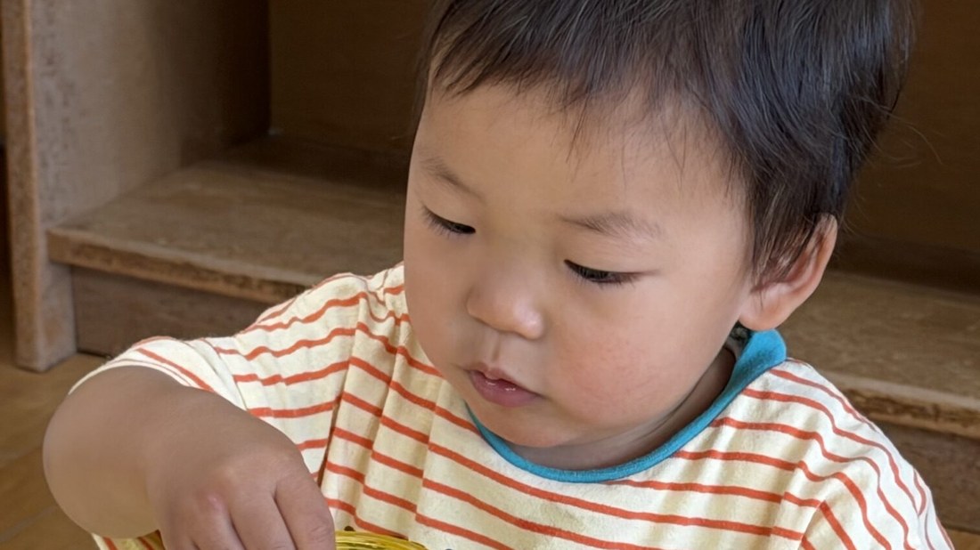 机に向かって教具で遊ぶ0〜2歳児