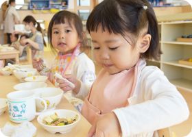 スプーンを持って給食を食べる子ども