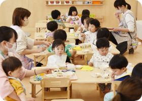保育者と一緒に給食を食べる子どもたち