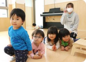 ピアノのそばで保育者と過ごす子どもたち