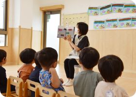 朝のお集まりで保育者の話を聞く子どもたち