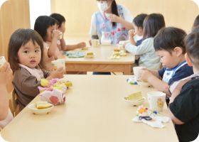 テーブルを囲んで午後のおやつを楽しむ子どもたち