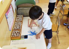 文字の教具を使って言葉を並べる園児