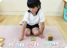 マットに教具を広げて数の活動に取り組む園児