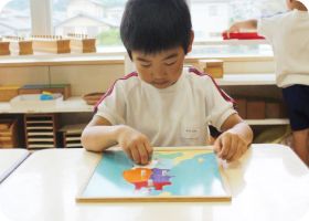 日本地図のパズル教具に取り組む園児