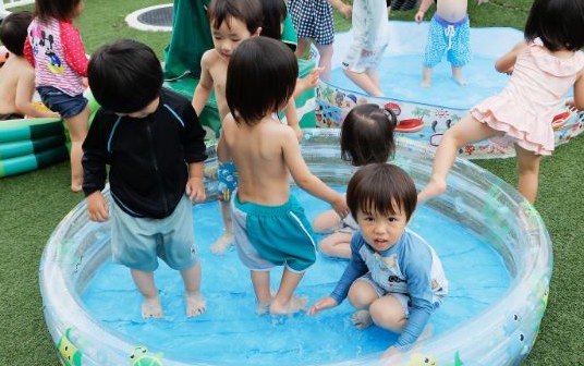 ビニールプールで水遊びを楽しむ園児たち